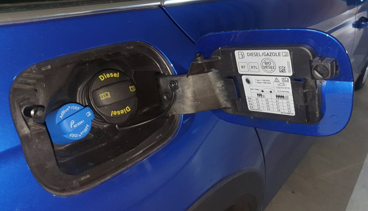 Otevřená dvířka nádrže s černým víčkem nafty, modrým víčkem AdBlue a štítkem se značkami B7 a XTL