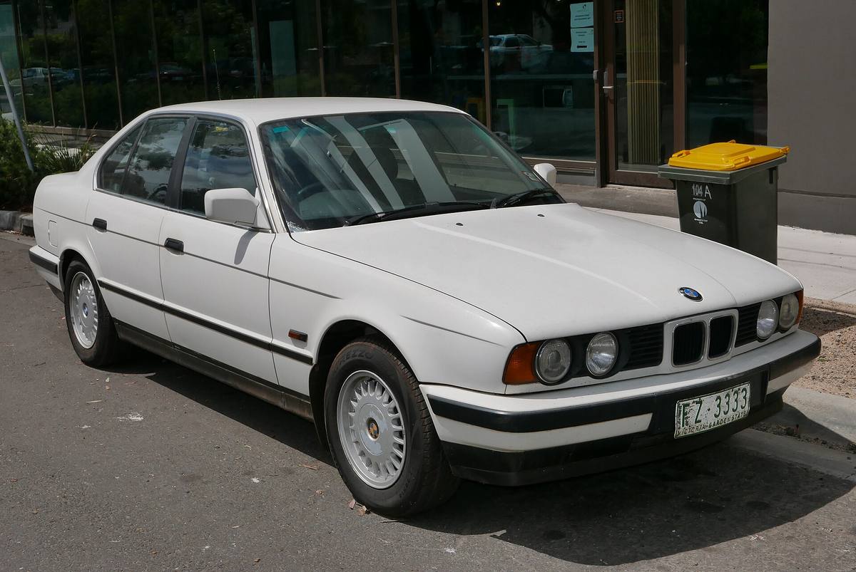 Bílé BMW 525i generace E34 zaparkované u chodníku