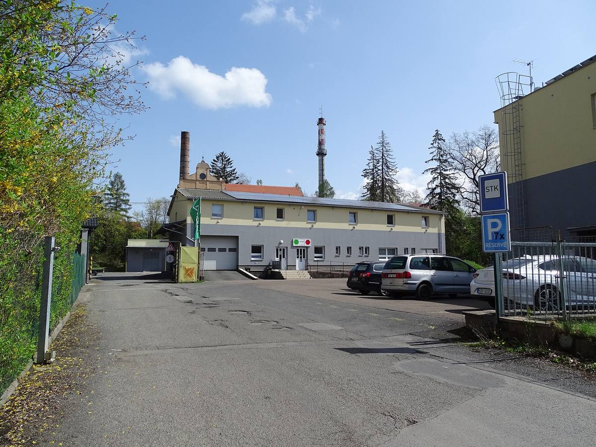 Budova stanice technické kontroly v Rokycanech s modrou značkou STK u vjezdu